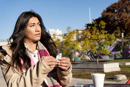 Beautifull Latin Woman adding sugar to coffee on the terrace of a cafe on a sunny day. Relaxation...