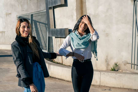 Two beautiful happy smiling women walking through an urban setting. Joy and happiness concept.