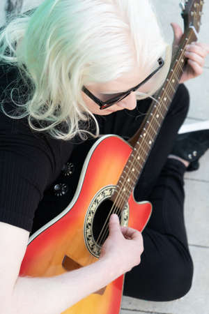 Young albino man playing guitar. Aerial view. Horizontal orientation. Concept art.