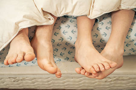feet of a couple under the blanket Love Concept.