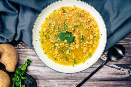Exquisite chicken and vegetable soup with small noodles and parsley, made at home. Zenital view. Natural and healthy food conceptの写真素材