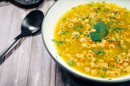 Exquisite chicken and vegetable soup with small noodles and parsley, made at home. Top view, copy space. Natural and healthy food conceptの写真素材