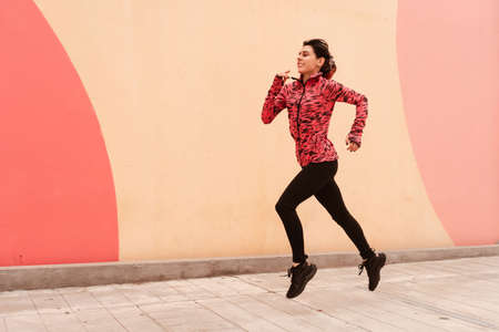 Young dark haired athlete woman doing sprint sprinting outdoors. Concept of full life, natural and healthy life. Women's sports.の写真素材