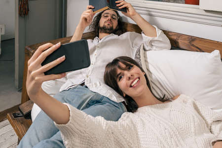 Young couple comfortable on a sofa taking a selfie with the cell phone. Couple concept.