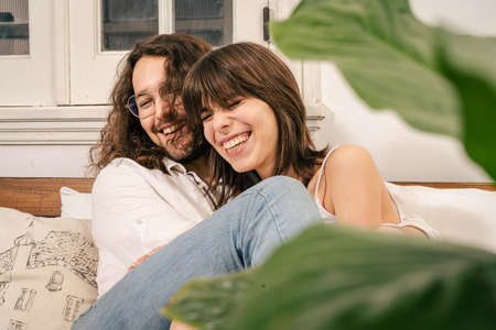 Young couple sitting on a sofa laughing and sharing a romantic and joyful moment.
