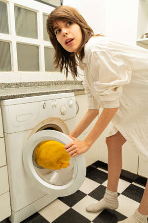 Young  woman putting dirty clothes in the washing machine.の写真素材