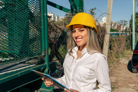 Beautiful young female engineer  wearing a safety helmet and inspecting a railroad pedestrian...