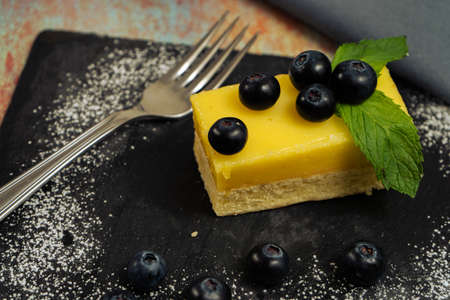 One Portion of homemade lemon curd cake in the shape of an ingot or brick decorated with some mint...