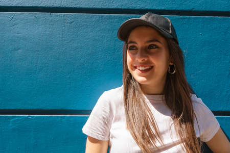 A Portrait of a young Hispanic woman smiling with space for text and with a blue background. Copy space.の写真素材