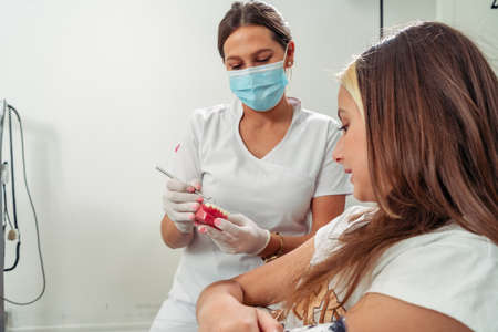 One Dentist explaining to an adolescent patient the treatment to be carried out with the help of an...