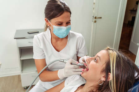young Female dentist performing a lathe treatment on an adolescent patient. Concept dental care, health care.の写真素材