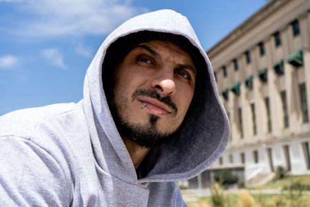 a PORTRAIT of a Young Latino with a gray hoodie looking into infinity. Marginal urban style.の写真素材