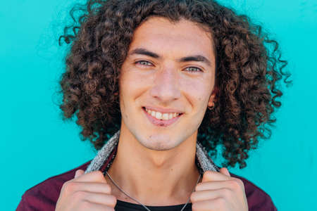 A closeup of the face of a smiling young latin man with a light green backgroundの写真素材