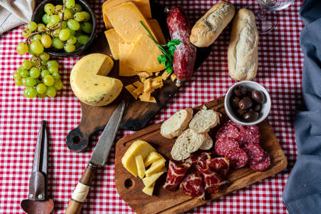 An overhead view of some delicious boards of cheeses and salami and pickles on a rustic table. Concept of natural, organic and healthy food.の写真素材