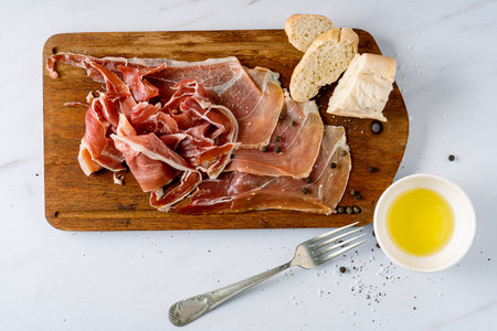 Arrangement of an exquisite Spanish serrano ham on a cutting board with olive oil and bread. Top view.の写真素材