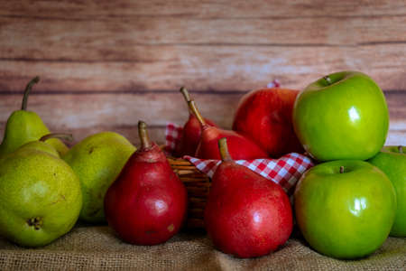 Normal view of some green and red pears and green and red apples in a basket and on a table. Organic and natural products, healthy food.の写真素材