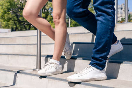 An unrecognizable Caucasian or Hispanic couple in casual attire walking down a concrete stairs. Horizontal orientation.の写真素材