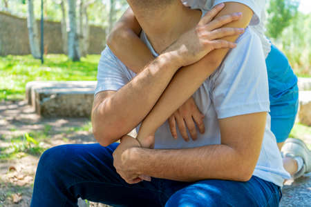A woman hugging the man from behind in a park. She unrecognizable couple in love and happy. Concept of love, couple, happiness.の写真素材