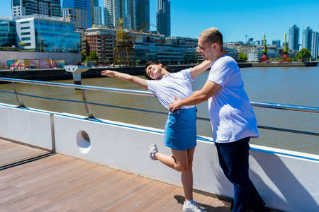 A portrait of a happy young couple walking on a bridge in the port. Concept of love, couple,...