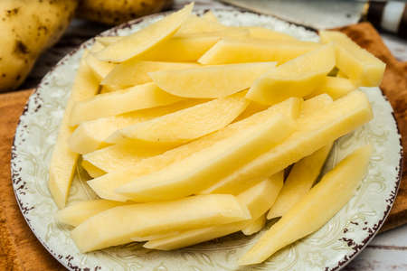 Dish with raw cane potatoes to make french fries. Chopped or high view. close up.の写真素材