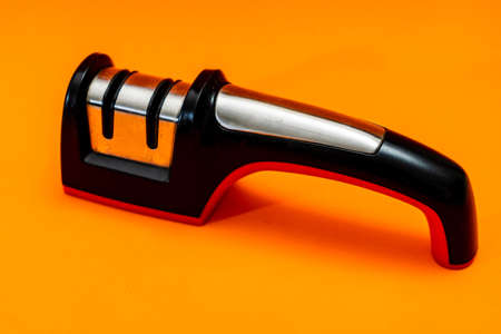 Knife sharpener isolated on an orange background.の写真素材