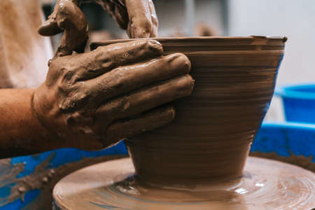 The skilled Hands of a potter working clay on a potter's wheel. The clay takes the shape the potter...