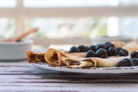 Delicious plate with homemade pancakes or crepes filled with dulce de leche and blueberries and icing sugar covering the plate. normalview.の写真素材