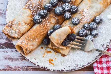 Dish with delicious homemade pancakes or crepes filled with dulce de leche. Fork with a bite and...