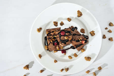 Chocolate brownie squares with walnut pieces, chocolate threads and granola. Natural, healthy food concept. Top view. copyspace.の写真素材