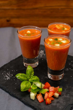 Small glasses of shot or liqueur with Andalusian Gazpacho. A cold vegetable and organic soup or drink that is drunk in summer or hot days. Vertical orientation. High view.の写真素材