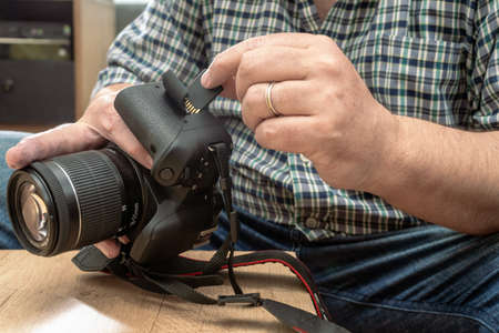 Male photographer inserting a flash memory card while holding a professional camera.