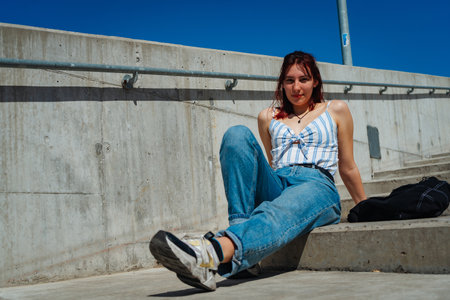Beautiful red-haired young woman lying comfortably on a staircase outdoors.