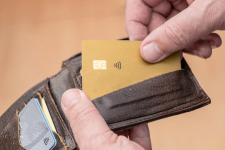 Close-up of a man's hand taking out a credit card from a personal document holder or wallet.