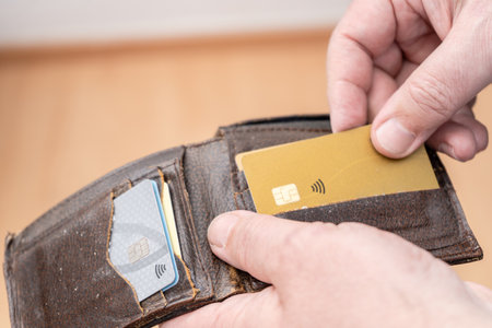 Close-up of a man's hand taking out a credit card from a personal document holder or wallet.