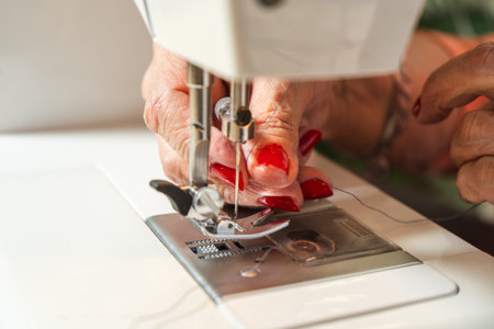 Seamstress threading the sewing machine needle before starting.の写真素材