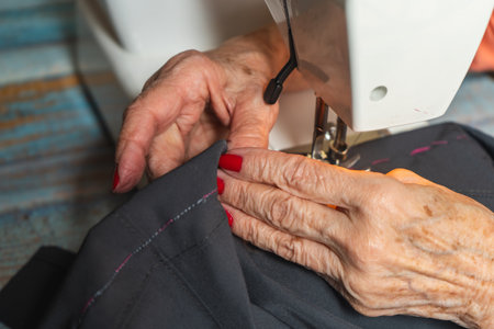 Hands of a seamstress sewing a pair of pants on a sewing machine.の写真素材