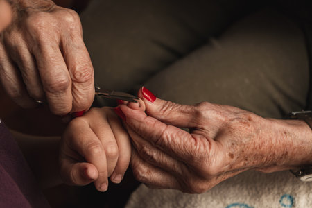 A granddaughter and her grandmother cutting her nailsの写真素材
