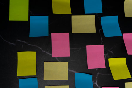 Colorful sticky notes arranged on black surface for creative idea organization. Aerial view.の写真素材