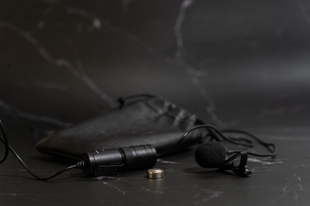 Lavalier microphone on a black background with a spare battery.の写真素材