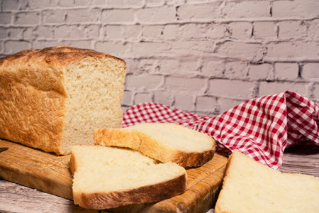 A White bread loaf on a cutting board next to a freshly cut slice.