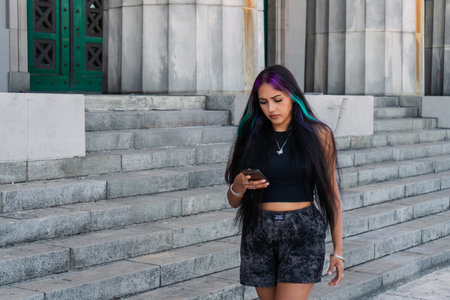 A young woman walking along the steps while checking and answering cell phone messagesの写真素材