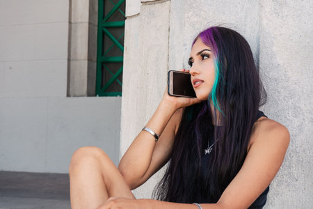 A young woman sitting talking on her cell phone on a staircase landingの写真素材