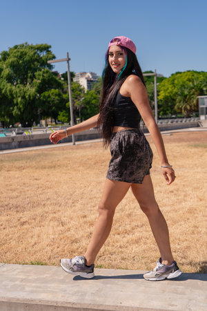 Young woman walking on the sidewalk next to the building.