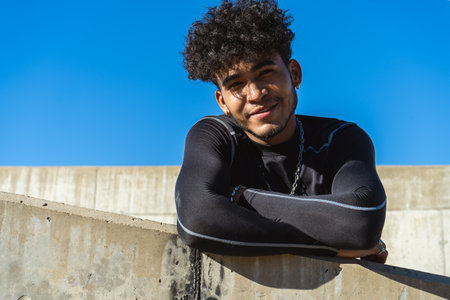 Portrait of a young Hispanic man with a friendly and jovial expression leaning on a constructionの写真素材