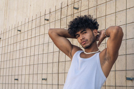 A handsome young man with a muscle t-shirt posing in front of a large concrete wall.の写真素材