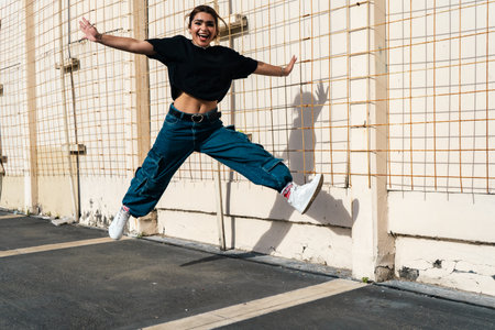Energetic woman jumping high with a cheerful expression outdoorsの写真素材