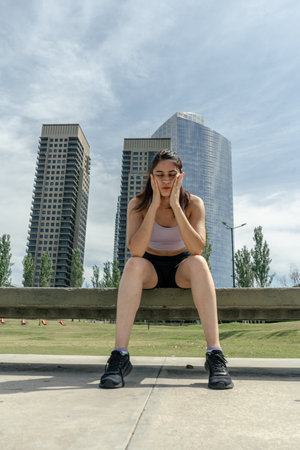 Young woman taking a break on a bench after exercising outdoorsの写真素材