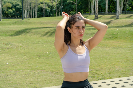 Sporty woman tying hair in urban park after workout