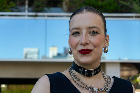 Portrait of a fashionable young woman smiling confidently, wearing a choker and metal chains