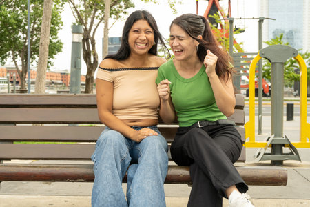 Two friends enjoying time together, laughing and sharing a moment of happiness in a city parkの写真素材